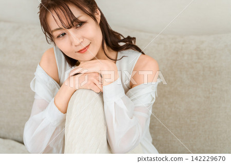 A middle-aged woman relaxing on her sofa at home. A middle-aged woman relaxing on her sofa at home. 142229670