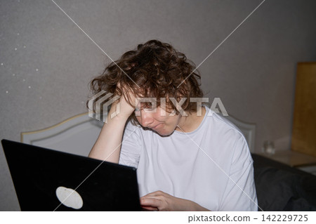 Woman Holding Head While Looking At Laptop In Bedroom Workspace, Expressing Mental Fatigue, Stress Woman Holding Head While Looking At Laptop In Bedroom Workspace, Expressing Mental Fatigue, Stress 142229725