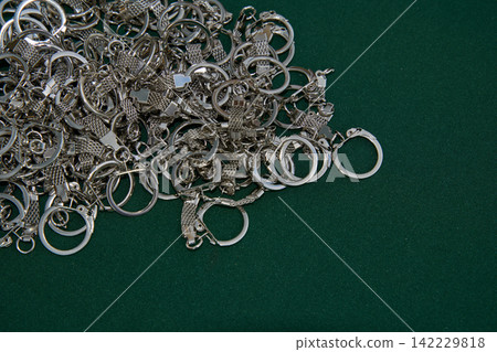 Pile Of Silver Key Rings And Chain Links Scattered Across Green Felt Surface In Close-Up Indoor Pile Of Silver Key Rings And Chain Links Scattered Across Green Felt Surface In Close-Up Indoor 142229818
