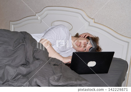 Woman Sleeping Beside Open Laptop While Lying Under Gray Blanket In Bedroom After Remote Work Woman Sleeping Beside Open Laptop While Lying Under Gray Blanket In Bedroom After Remote Work 142229871