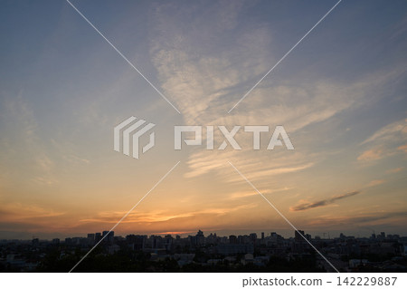 City Skyline Silhouetted Beneath Warm Sunset Clouds Over Wide Urban Horizon City Skyline Silhouetted Beneath Warm Sunset Clouds Over Wide Urban Horizon 142229887