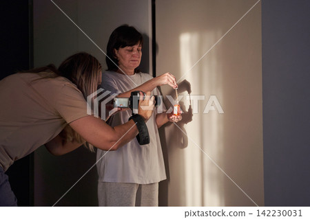 Photographer Capturing Woman Holding Amber Serum Bottle With Pipette Against Softly Lit Interior Photographer Capturing Woman Holding Amber Serum Bottle With Pipette Against Softly Lit Interior 142230031