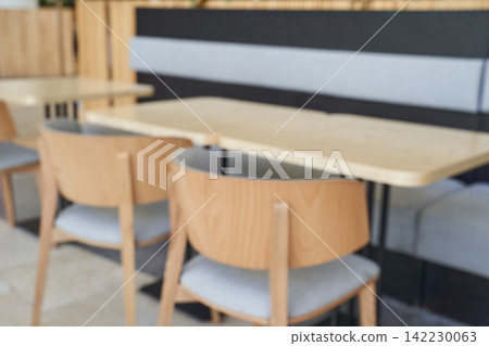 Wooden Chairs Pushed Under Light Wood Tables In Modern Cafe Interior With Upholstered Banquette 142230063