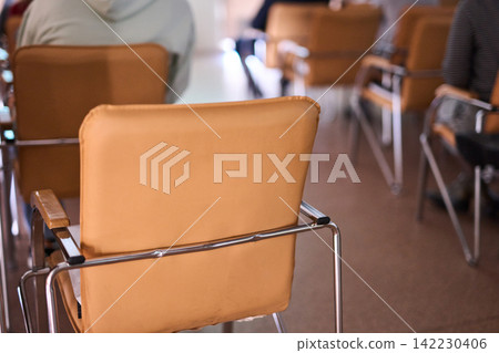 Leather Chair Backrest In Lecture Hall Row With Chrome Frame And Neighboring Chairs Blurred Leather Chair Backrest In Lecture Hall Row With Chrome Frame And Neighboring Chairs Blurred 142230406