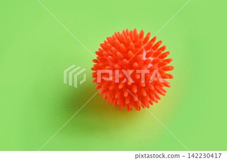 Closeup Of Orange Spiky Massage Ball On Green Background Showing Dense Rubber Spikes, Tactile Closeup Of Orange Spiky Massage Ball On Green Background Showing Dense Rubber Spikes, Tactile 142230417