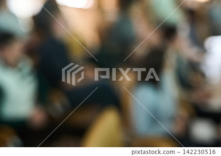 Blurred Group Sitting In Rows During Conference Session With Mixed Seating And Soft Warm Tones Blurred Group Sitting In Rows During Conference Session With Mixed Seating And Soft Warm Tones 142230516