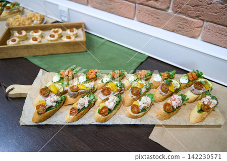 Row Of Assorted Bruschetta With Seafood Cream Roasted Tomatoes And Herbs Displayed On Parchment Row Of Assorted Bruschetta With Seafood Cream Roasted Tomatoes And Herbs Displayed On Parchment 142230571