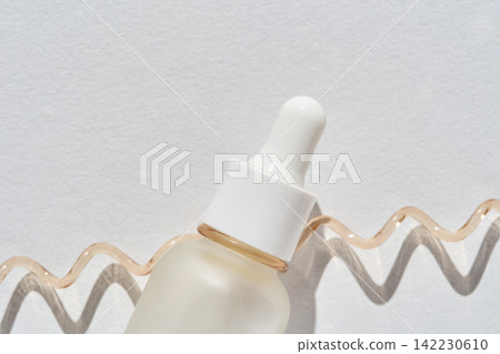 Frosted Glass Dropper Bottle Lying Horizontally On White Textured Paper With Curved Serum Trail 142230610