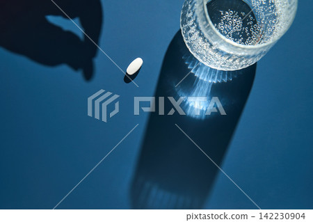 Glass Bottle Top With Effervescent Water Beside Single White Tablet And Reaching Hand Shadow Glass Bottle Top With Effervescent Water Beside Single White Tablet And Reaching Hand Shadow 142230904