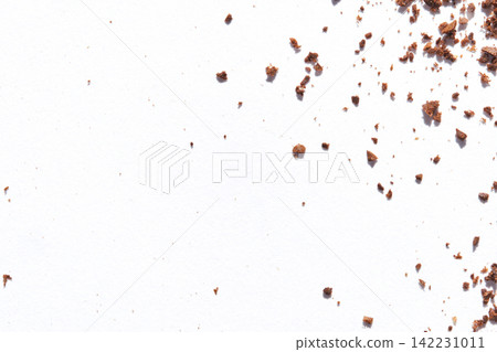 Corner Cluster Of Ground Coffee Crumbs On White Paper With Scattered Fragments Toward Center Corner Cluster Of Ground Coffee Crumbs On White Paper With Scattered Fragments Toward Center 142231011