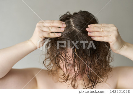 Woman Examining Wet Hair Parting Scalp With Hands Top Of Head Closeup Looking Down Neutral 142231038