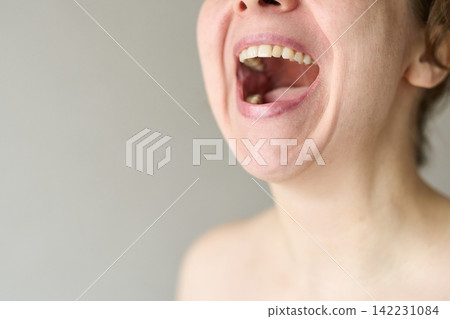 Woman Opening Mouth Wide In Laughing Shout With Visible Teeth And Bare Shoulders Against Plain Gray Woman Opening Mouth Wide In Laughing Shout With Visible Teeth And Bare Shoulders Against Plain Gray 142231084