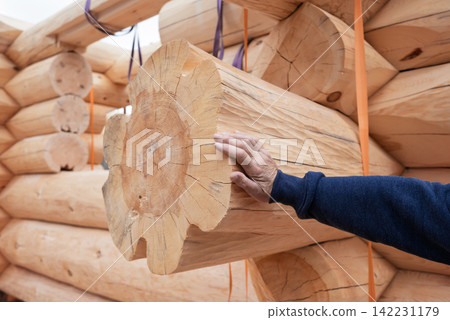 The construction site of a wooden house. Traditional log cabin built from wood logs on sunny summer day. Cottage house design The construction site of a wooden house. Traditional log cabin built from wood logs on sunny summer day. Cottage house design 142231179
