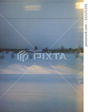 Snow Covered Rural Landscape Stretching Under Overcast Sky With Distant Houses And Trees Visible Snow Covered Rural Landscape Stretching Under Overcast Sky With Distant Houses And Trees Visible 142231203