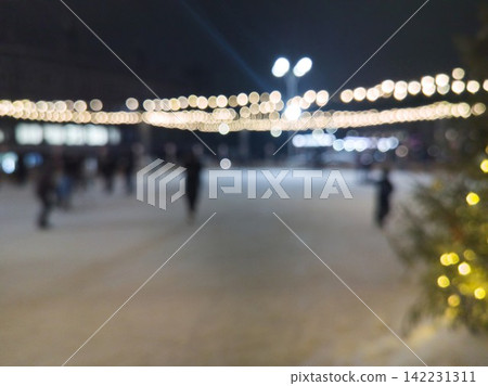 Outdoor Ice Rink With Blurred Skaters Moving Under String Lights And Illuminated Decorations 142231311