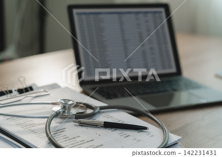 Stethoscope resting on a printed financial report beside a pen, tablet and laptop spreadsheet, illustrating healthcare financial analysis, medical expense review and reporting workflow. Stethoscope resting on a printed financial report beside a pen, tablet and laptop spreadsheet, illustrating healthcare financial analysis, medical expense review and reporting workflow. 142231431