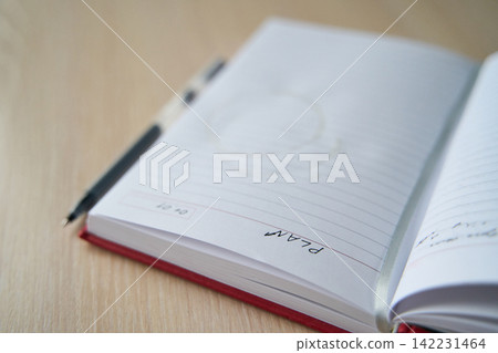 Red Notebook Opened Showing Lined Page With Handwritten Plan Note And Pen Placed On Wooden Table Red Notebook Opened Showing Lined Page With Handwritten Plan Note And Pen Placed On Wooden Table 142231464