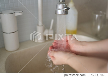 Hands Catching Running Tap Water Over Kitchen Sink With Beige Basin White Faucet And Soap Dispenser Hands Catching Running Tap Water Over Kitchen Sink With Beige Basin White Faucet And Soap Dispenser 142231469