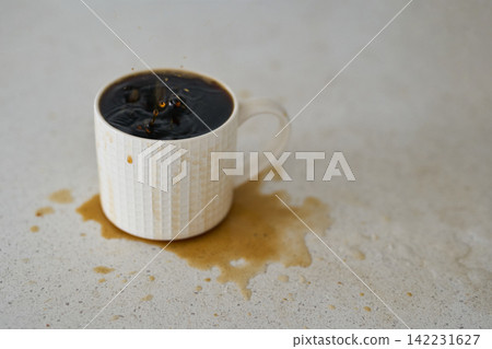 White Ceramic Mug With Black Coffee And Visible Surface Ripples Over Brown Spill On Speckled White Ceramic Mug With Black Coffee And Visible Surface Ripples Over Brown Spill On Speckled 142231627