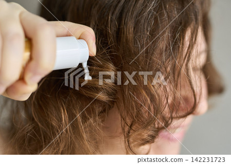 Woman Applying Conditioner To Damp Curly Brown Hair With Pump Bottle In Closeup Indoor Setting Woman Applying Conditioner To Damp Curly Brown Hair With Pump Bottle In Closeup Indoor Setting 142231723