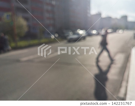 Single Pedestrian Crossing Busy Urban Road With Pronounced Shadow And Blurred Moving Vehicle Near Single Pedestrian Crossing Busy Urban Road With Pronounced Shadow And Blurred Moving Vehicle Near 142231767