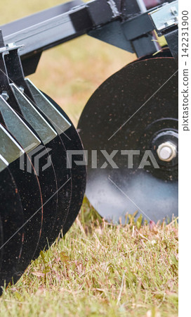 Disc Blades Cutting Soil On Grassy Field During Tillage Operation With Metal Harrow Mounted Disc Blades Cutting Soil On Grassy Field During Tillage Operation With Metal Harrow Mounted 142231900