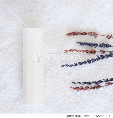 White Cosmetic Bottle Lying Horizontally Beside Dried Lavender Sprigs On Textured White Towel 142231903