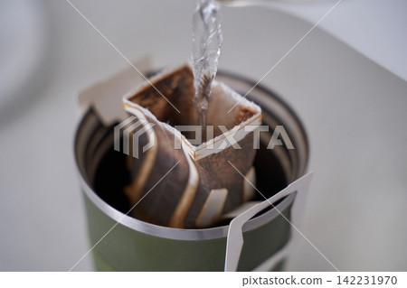 Drip Coffee Bag Pouring Hot Water Into Metal Travel Mug During Preparation On Kitchen Countertop 142231970