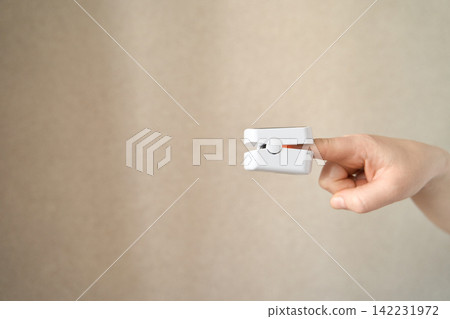 Single hand holding pulse oximeter device isolated showing portable healthcare monitoring equipment Single hand holding pulse oximeter device isolated showing portable healthcare monitoring equipment 142231972