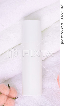 White Cosmetic Bottle Standing Upright On Folded White Towels With Pink Cotton Flowers On Soft White Cosmetic Bottle Standing Upright On Folded White Towels With Pink Cotton Flowers On Soft 142232021