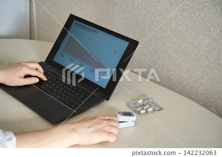 Person Checking Oxygen Level With Pulse Oximeter Beside Laptop And Blister Pack Of Pills On Table Person Checking Oxygen Level With Pulse Oximeter Beside Laptop And Blister Pack Of Pills On Table 142232063