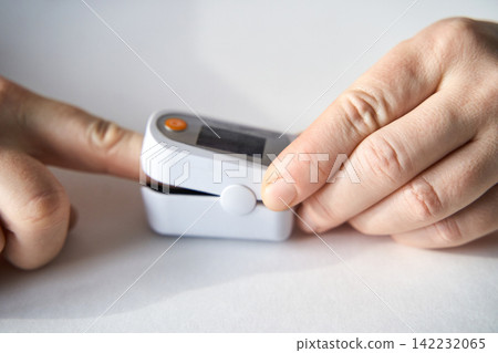 Pulse Oximeter Placed On Finger Being Held By Hands Measuring Oxygen Saturation And Pulse Rate Pulse Oximeter Placed On Finger Being Held By Hands Measuring Oxygen Saturation And Pulse Rate 142232065