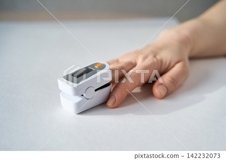 Hand With Pulse Oximeter Attached To Finger Showing Oxygen Saturation Measurement In Healthcare Hand With Pulse Oximeter Attached To Finger Showing Oxygen Saturation Measurement In Healthcare 142232073