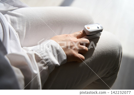 Pulse Oximeter Measuring Fingertip Oxygen Saturation On Hand Resting On Lap In Bright Sunlight Pulse Oximeter Measuring Fingertip Oxygen Saturation On Hand Resting On Lap In Bright Sunlight 142232077