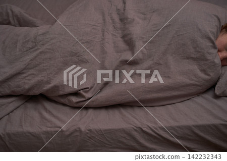 Caucasian young female sleeping under gray blanket on bed with soft textured fabric Caucasian young female sleeping under gray blanket on bed with soft textured fabric 142232343