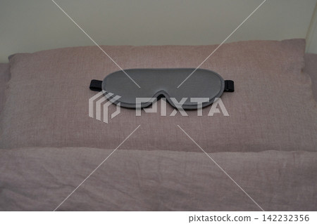 Gray sleep mask on lavender pillow for restful sleep and relaxation in a cozy bedroom setting Gray sleep mask on lavender pillow for restful sleep and relaxation in a cozy bedroom setting 142232356