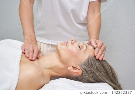 Mature caucasian woman enjoying relaxing massage therapy session in spa setting for wellness Mature caucasian woman enjoying relaxing massage therapy session in spa setting for wellness 142232357