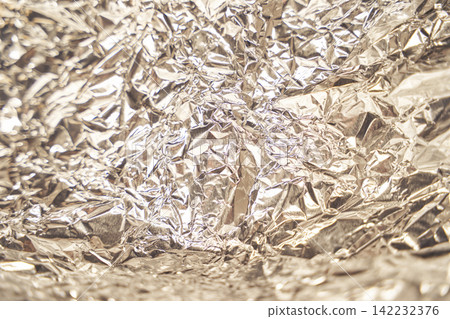 Crumpled reflective silver aluminum foil creating a textured metallic surface with light Crumpled reflective silver aluminum foil creating a textured metallic surface with light 142232376
