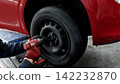 The hands of a car mechanic changing a tire 142232870