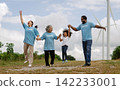 Family jumps joyfully on grassy hillside 142233001