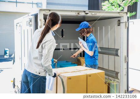Female driver and worker loading trucks Female driver and worker loading trucks 142233106