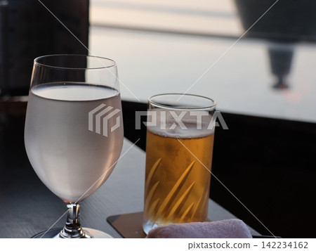 窗邊擺放著一排啤酒杯和水杯,陽光從窗外照射過來──這是放鬆的時刻。 窗邊擺放著一排啤酒杯和水杯,陽光從窗外照射過來──這是放鬆的時刻。 142234162