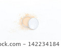Open compact reveals soft natural toned powder. Slight dusting suggests gentle application. Minimalist white background enhances product clarity. Ideal for beauty, skincare, or makeup editorial use 142234184