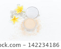 Soft powder spills from open container beside mirror. Yellow flowers add bright tropical flair. White coral fragment accents the clean minimalist scene. Ideal for beauty, skincare 142234186