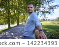 handsome mature man smiling while standing on sunny countryside path 142234393