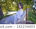 pregnant mature woman in floral dress walking on sunny rural pathway 142234403
