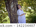 pregnant mature woman in floral dress walking on sunny rural pathway 142234407