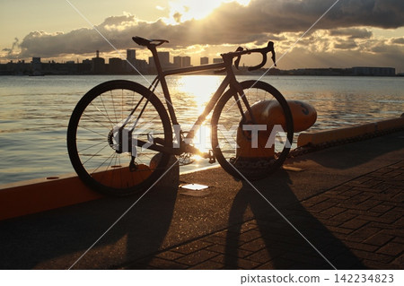 清晨的陽光照耀著神戶港,一輛公路自行車的輪廓清晰可見。 清晨的陽光照耀著神戶港,一輛公路自行車的輪廓清晰可見。 142234823