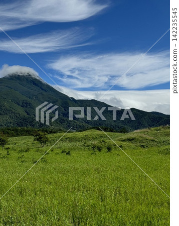 The Shiretoko mountain range and summer grasslands; mountains shrouded in clouds and a blue sky; a landscape of Shiretoko, Hokkaido. 142235545