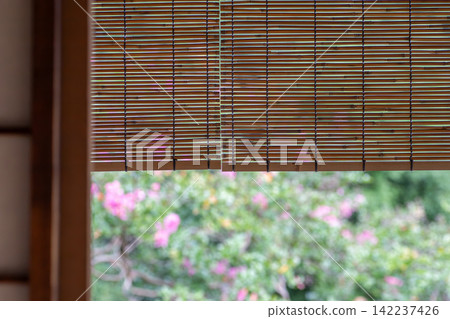 A window in a Japanese-style room with a bamboo blind. A view of the garden from the veranda. A window in a Japanese-style room with a bamboo blind. A view of the garden from the veranda. 142237426